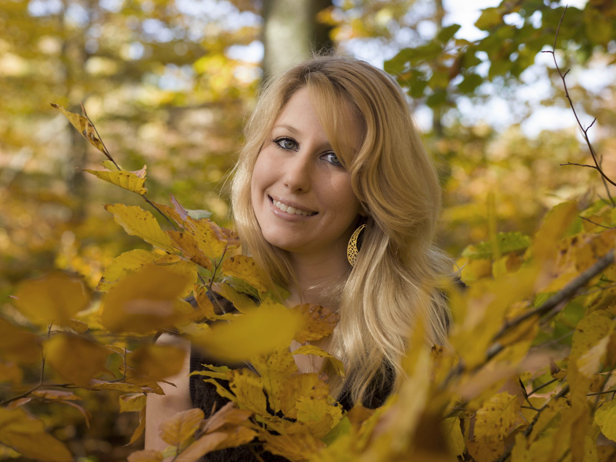 Natürliches Outdoor-Portrait einer jungen Frau zwischen Herbstblättern.