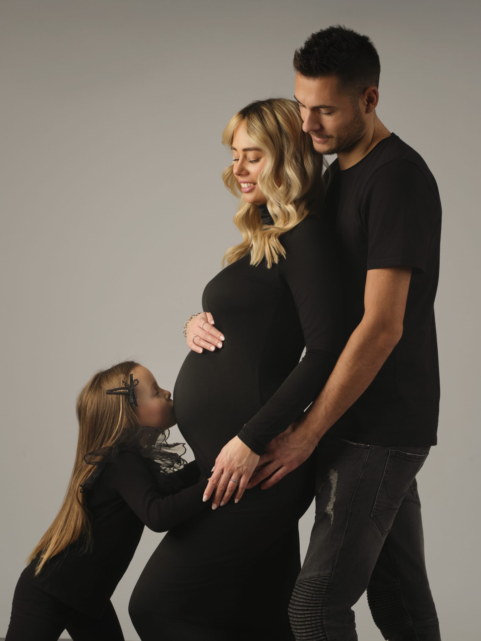 Schwangere Frau mit Partner und Tochter im Studio.