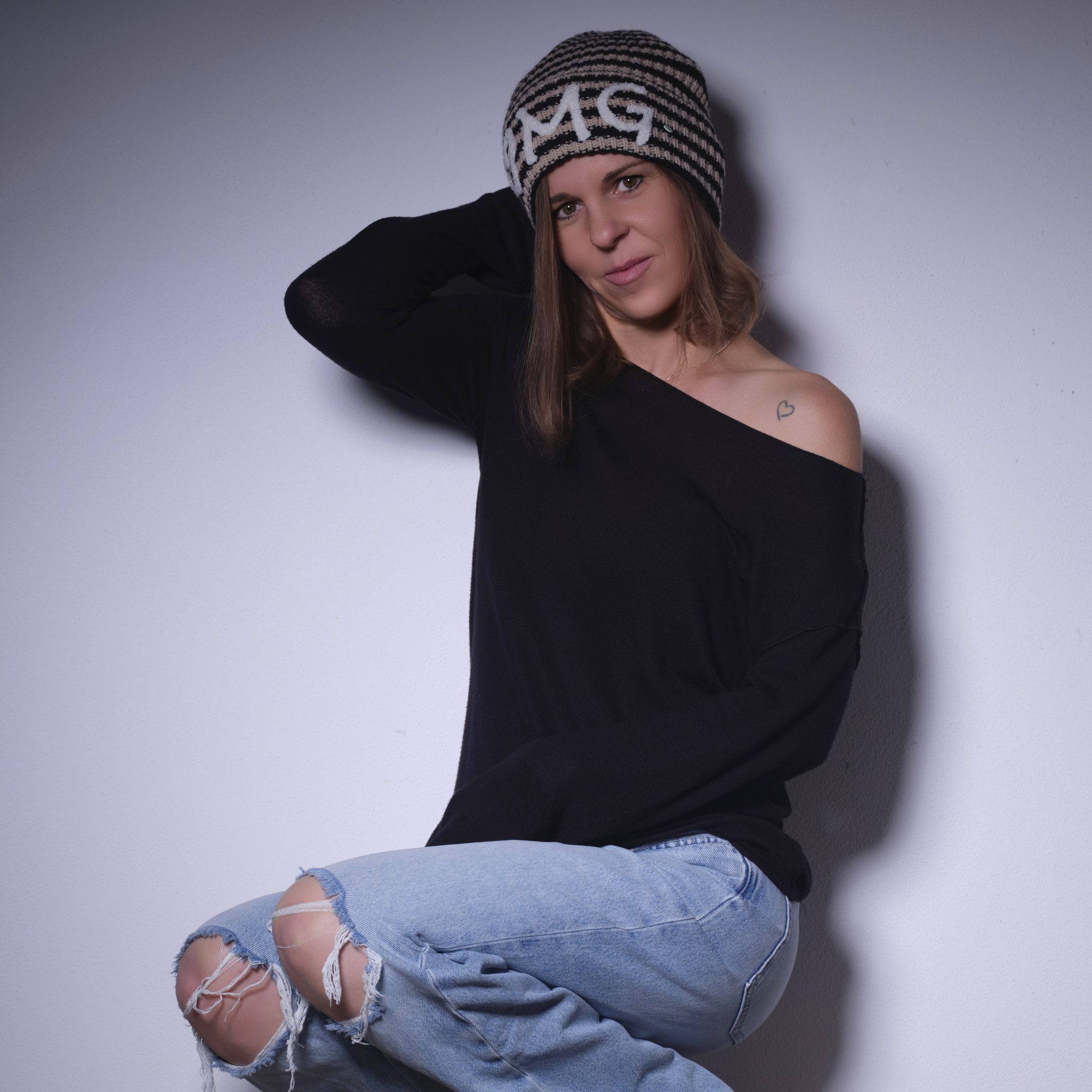 Studio-Portrait einer Frau im weißen Hemd vor warmer Kulisse.