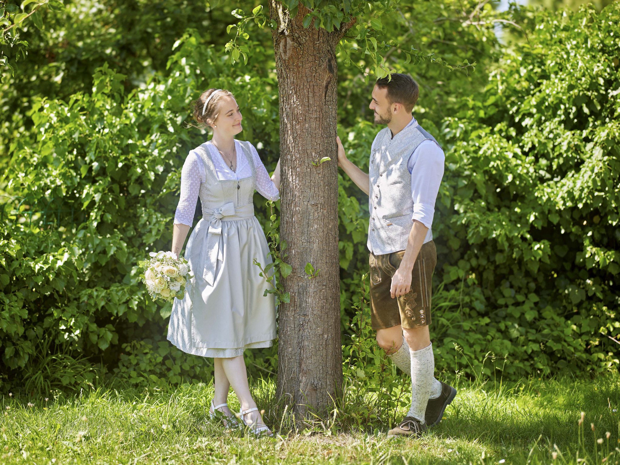 Brautpaar in Tracht zwischen Birken im Sommer.